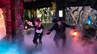 two men wearing pirate costumes and holding flame lights