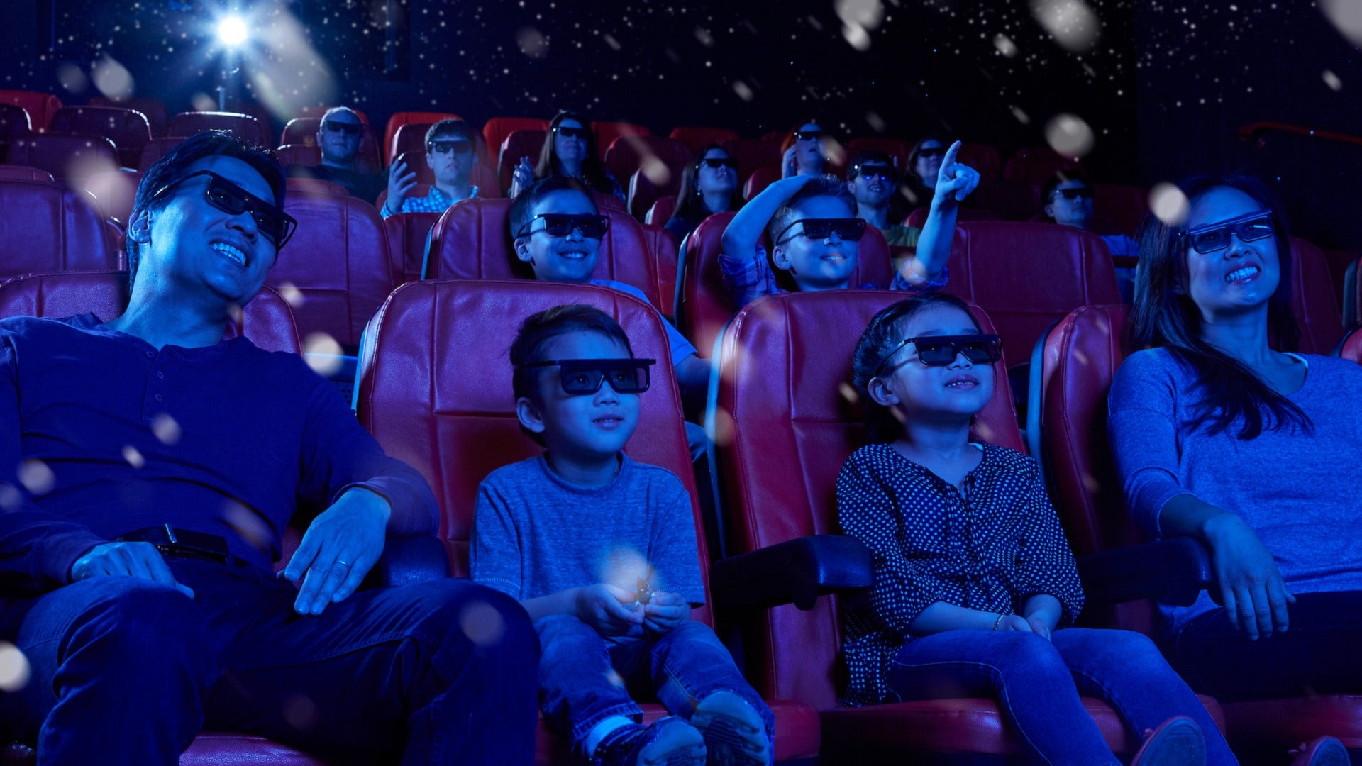 family and kids in an indoor theater wearing 3D glasses