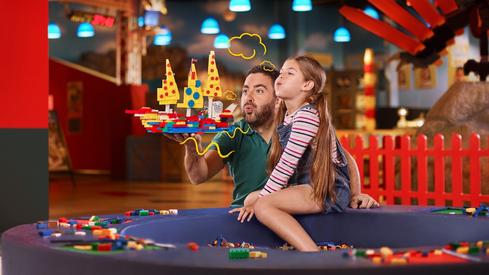 father and daughter playing with a boat made out of lego