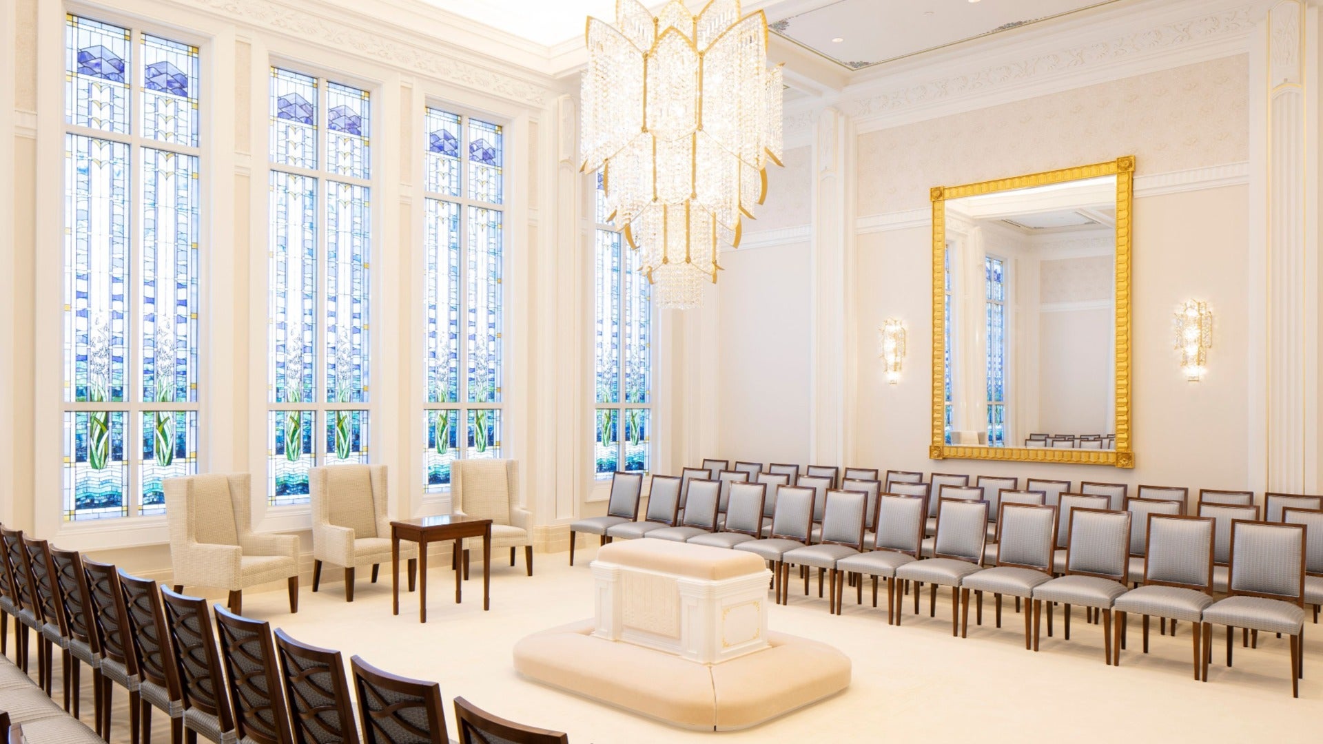 room with chairs and a pedestal, chandelier, and stained glass