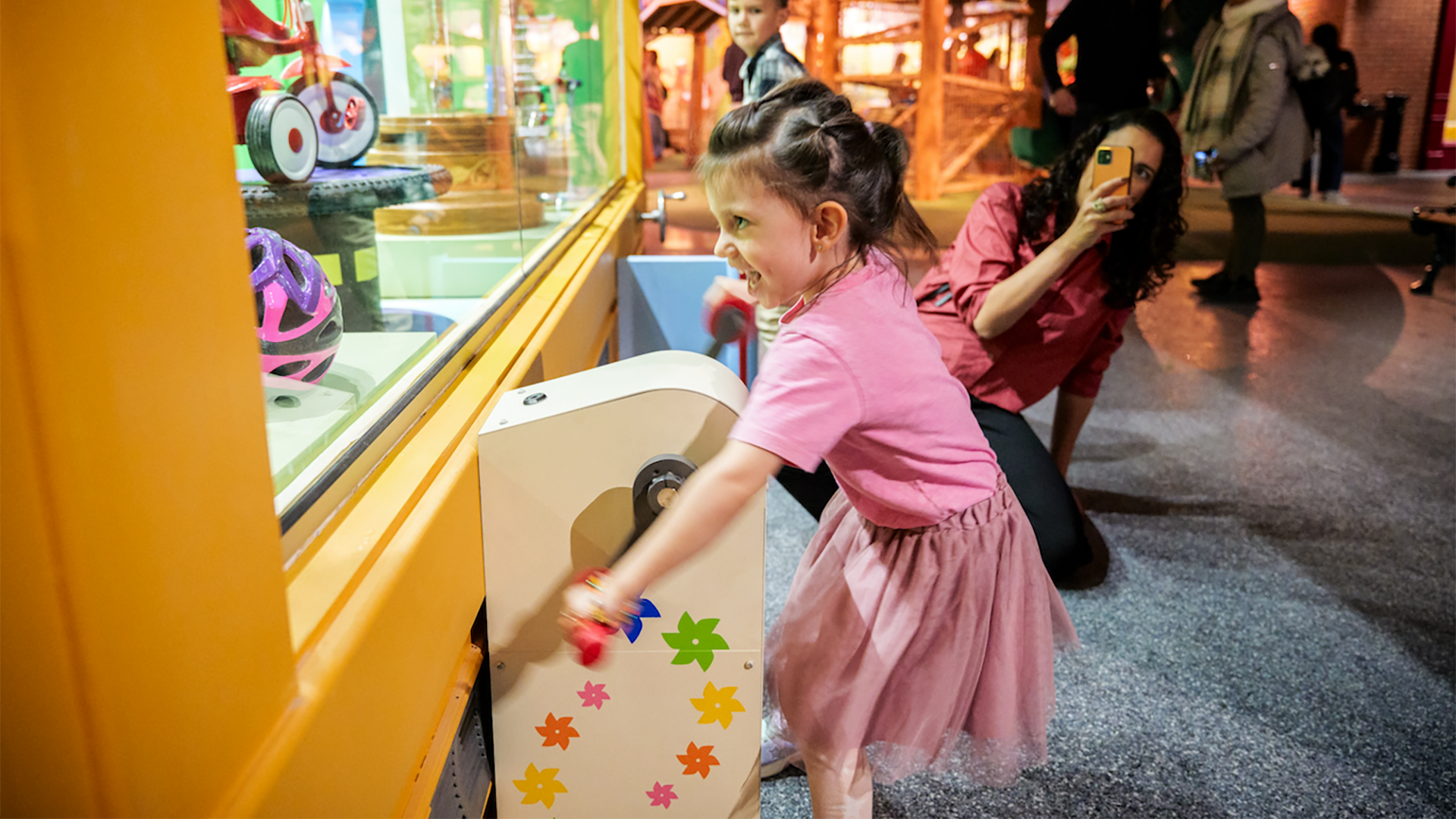child playing in an indoor play facility with an adult taking a photo of her