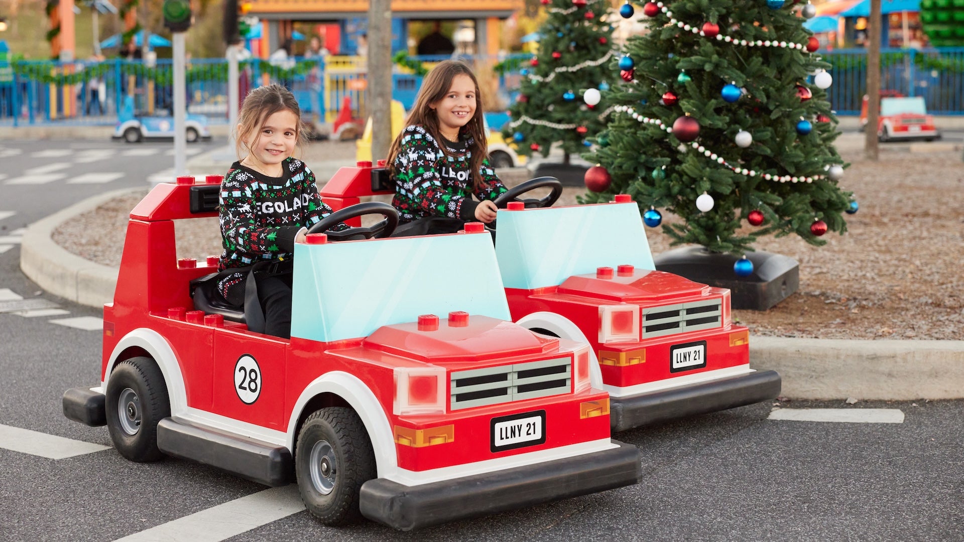 Two cars on a track with girls in Christmas outfits with a Christmas tree in the background