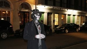 a man in a scary costume standing on the street with cars behind him