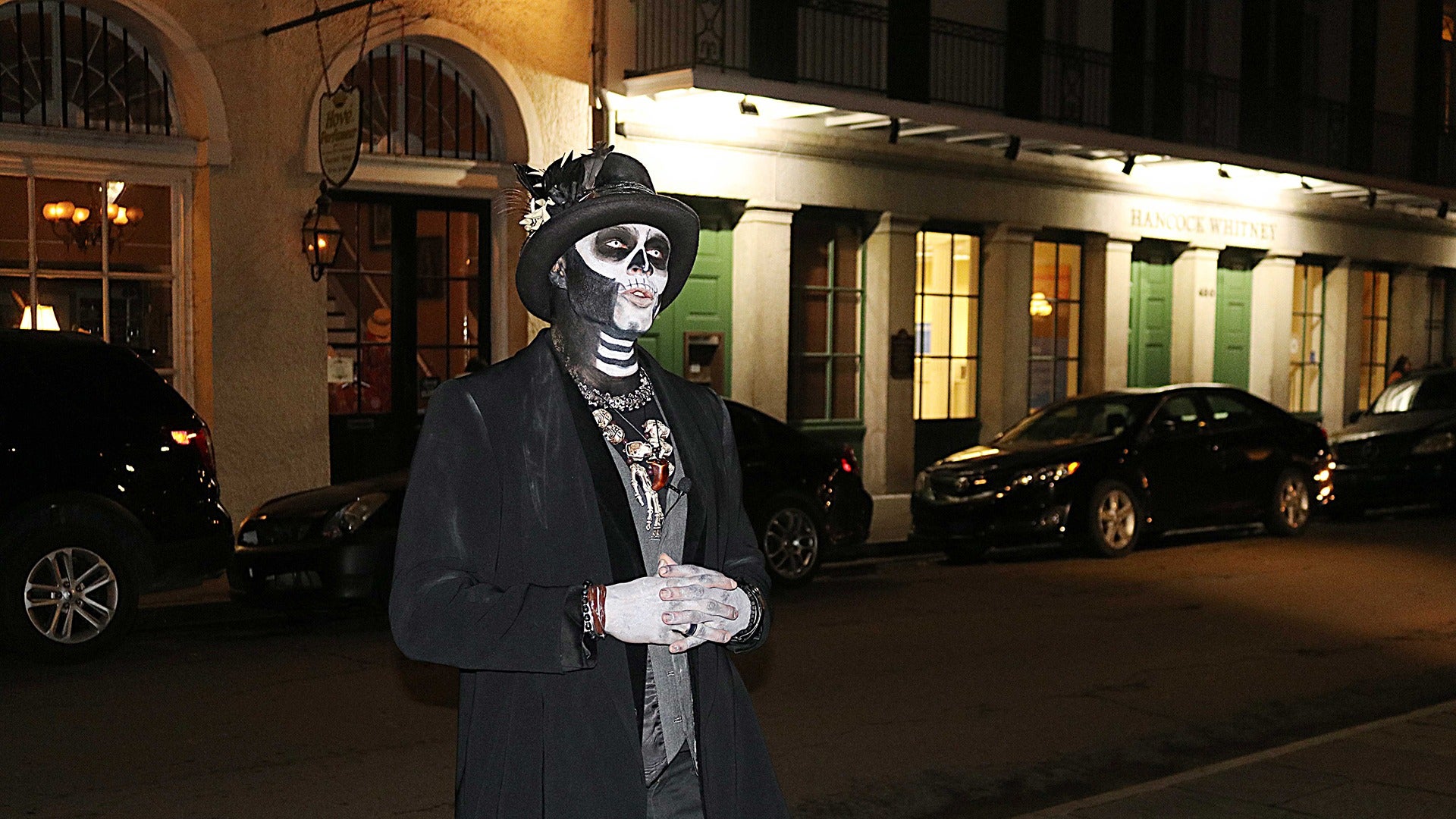 a man in a scary costume standing on the street with cars behind him