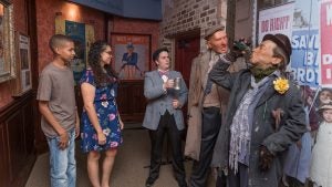 people looking at exhibits in a museum surrounded by posters
