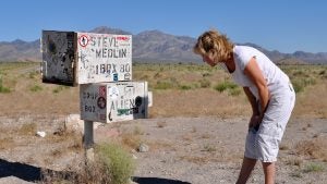 woman looking at a piece of vandalized boxes in the desert