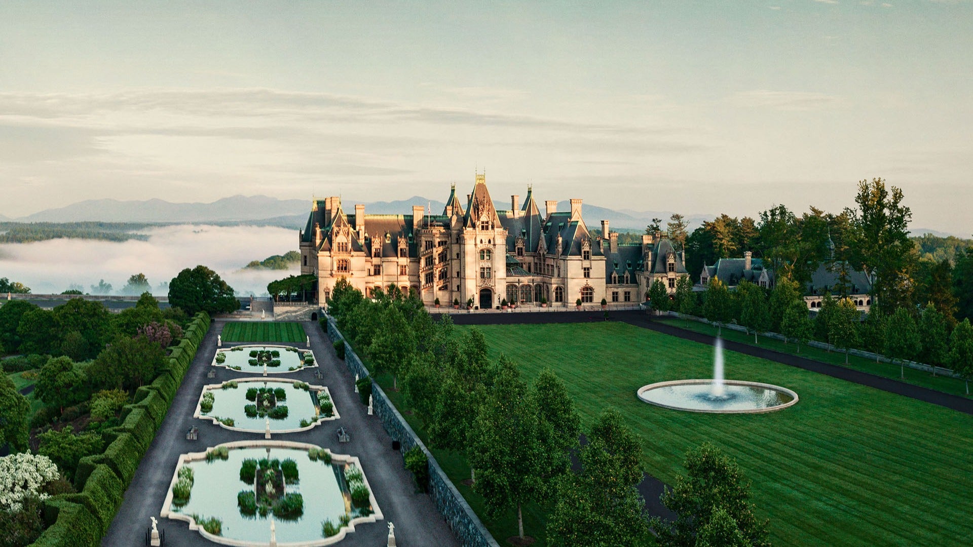 mansion with sprawling gardens, fountains, and big trees