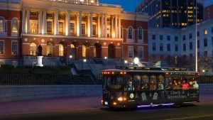 tour trolley with passengers passing by a building