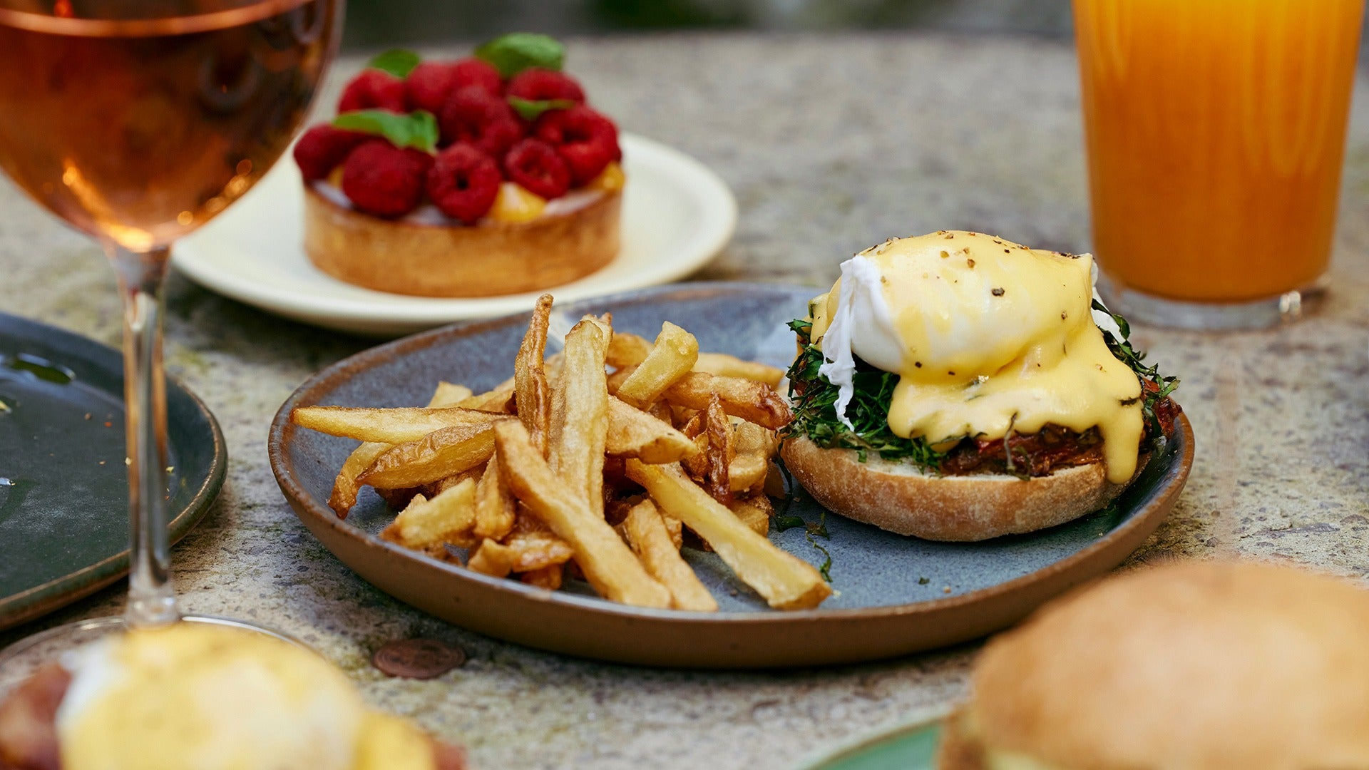 eggs benedict with a side of fries, champagne, and pastry at the back