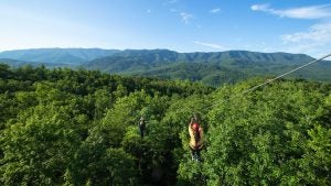two people going down a zipline with mountain view