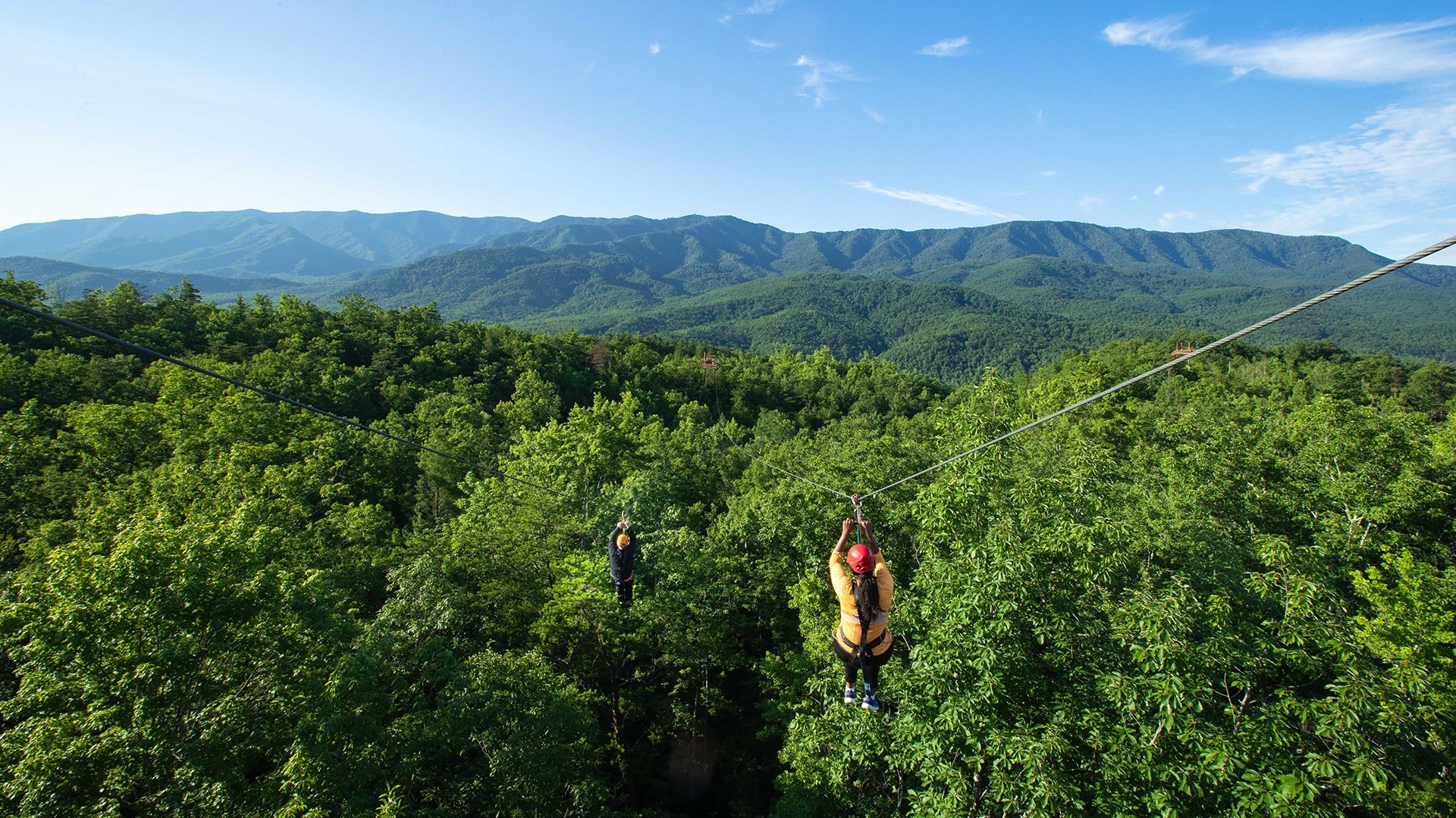 two people going down a zipline with mountain view