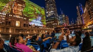 people on a river cruise passing by buildings and taking photos