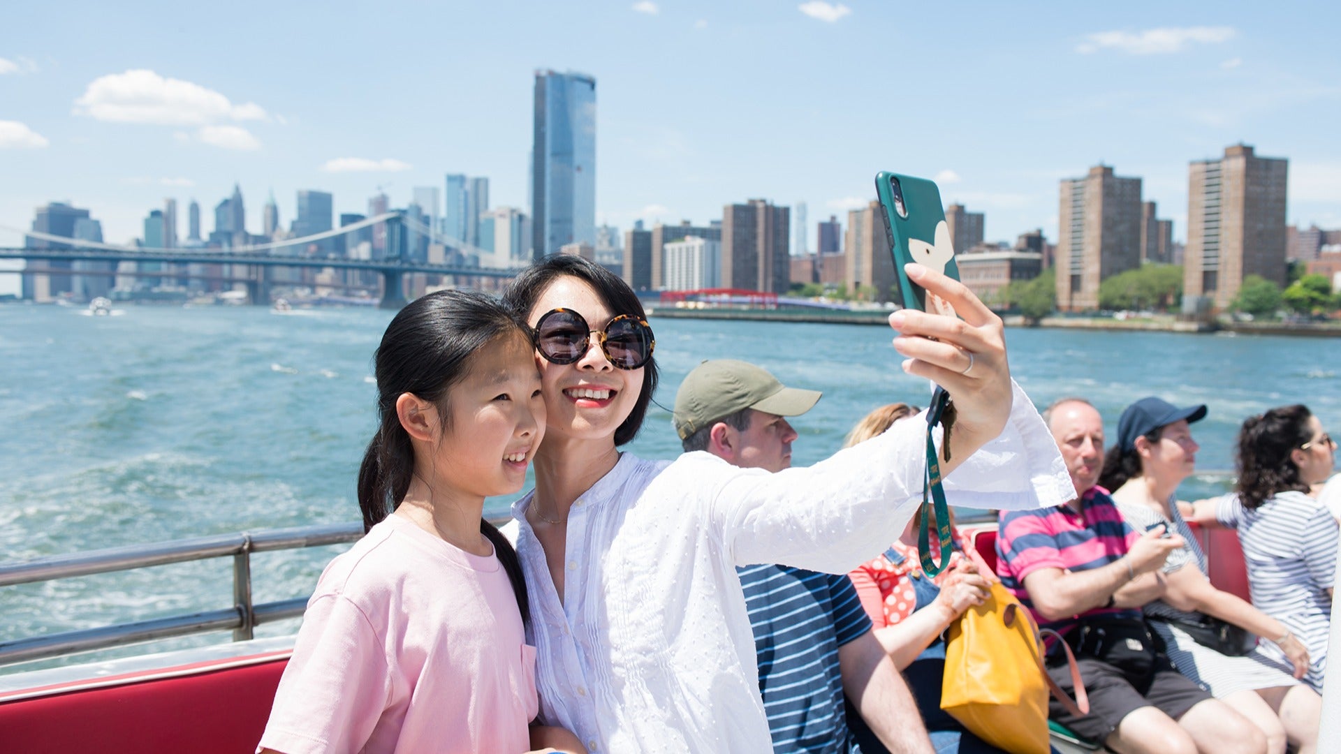 mom and daughter taking a selfie on a cruise with nyc skyline behind