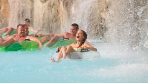 people on floaties having fun under a water feature