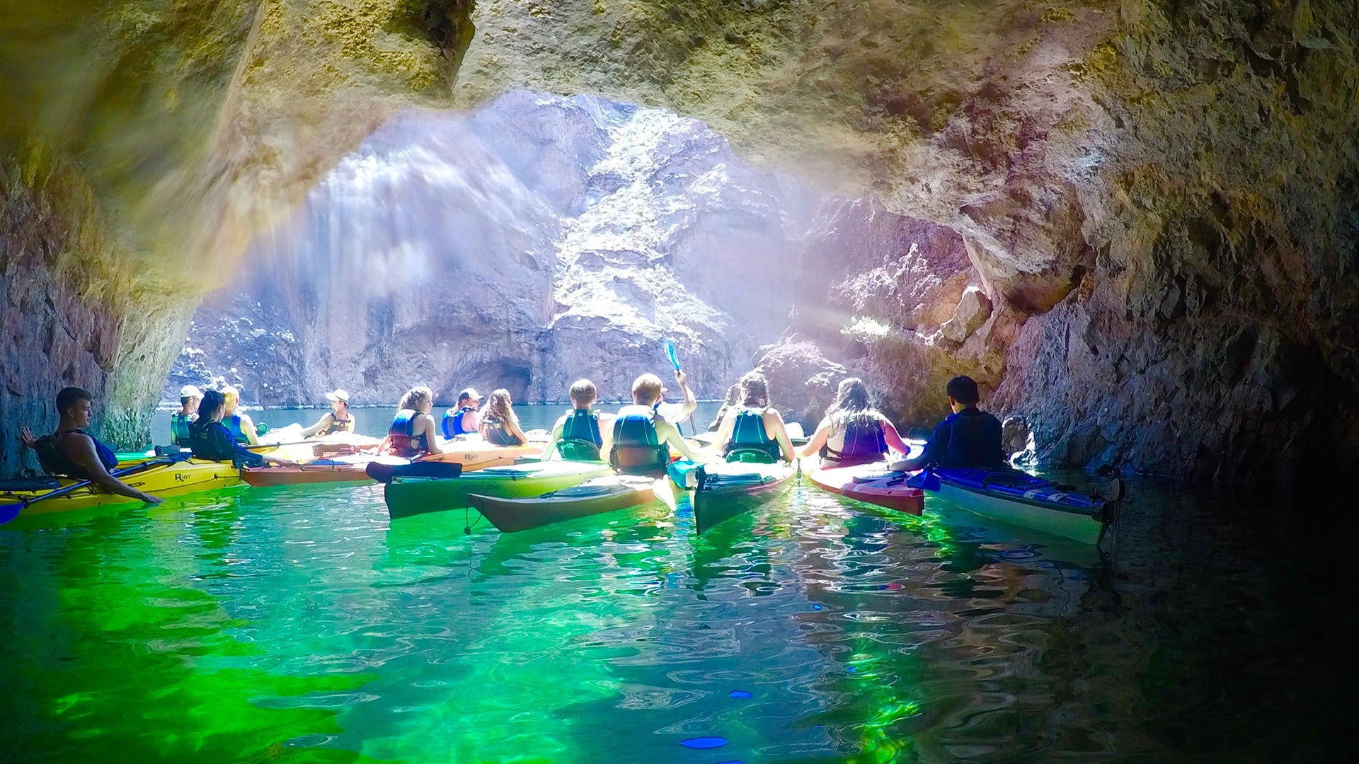 people on kayaks passing through a cave