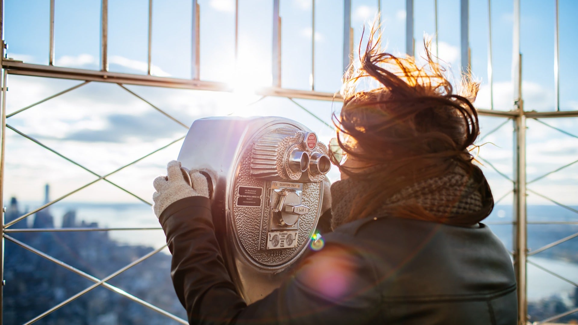 woman looking through a telescope above a building