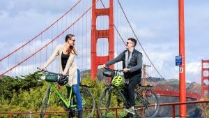 couple biking with a view of the golden gate bridge at the back