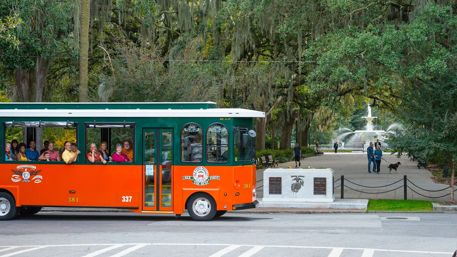 trolley tour strolling through town passing by a park with a fountain