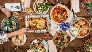 spread of italian food including lasagna, pizza, salads, with people eating