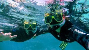 two people wearing goggles and snorkeling gear in the ocean