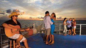 a couple dancing to live music by someone playing the guitar on a cruise