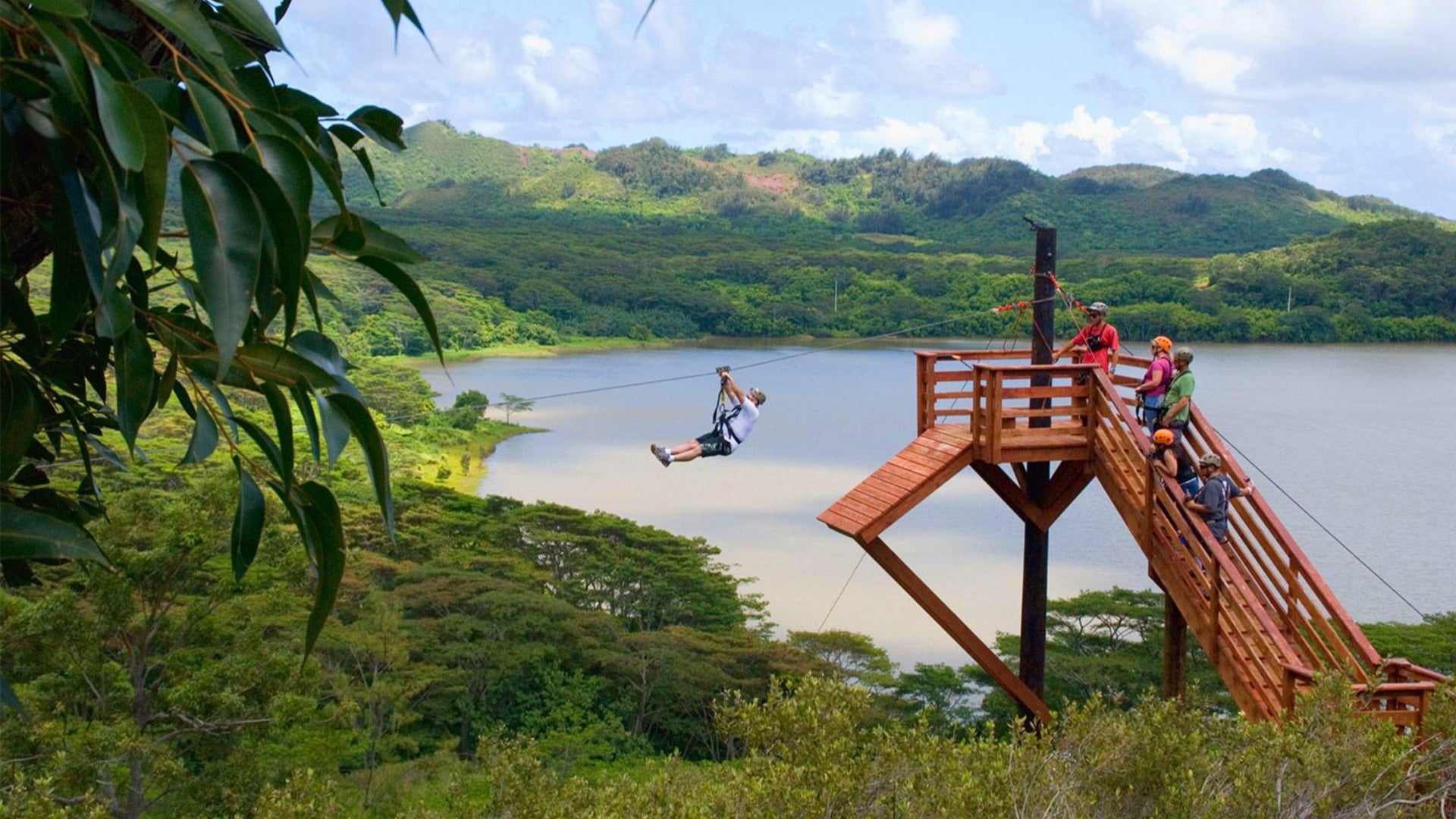 person going down a zipline with instructors behind him