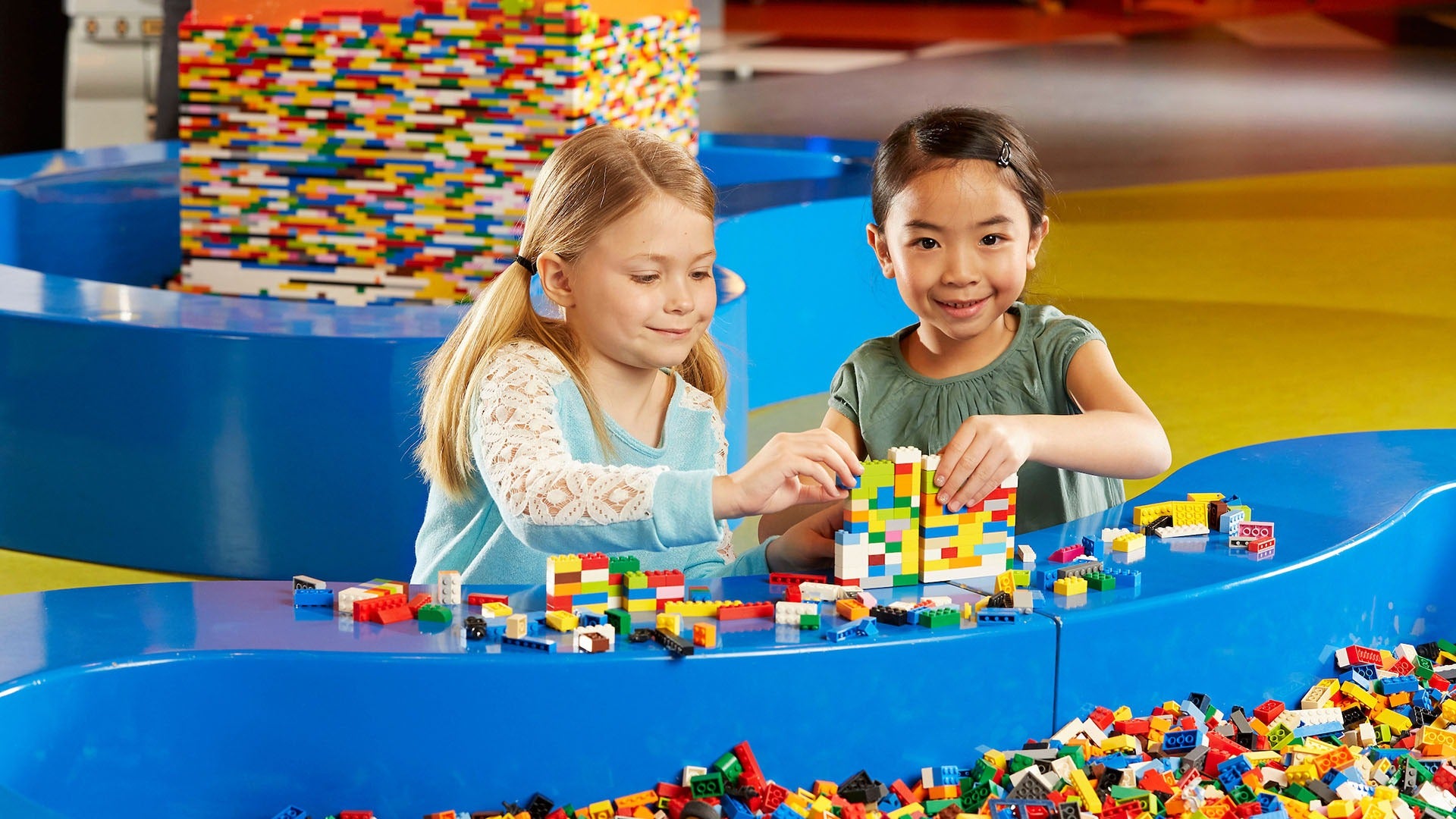 two little girls playing with legos in a lego pit