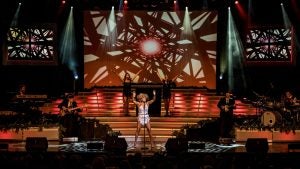 a performer in costume on stage with a band and backup singers