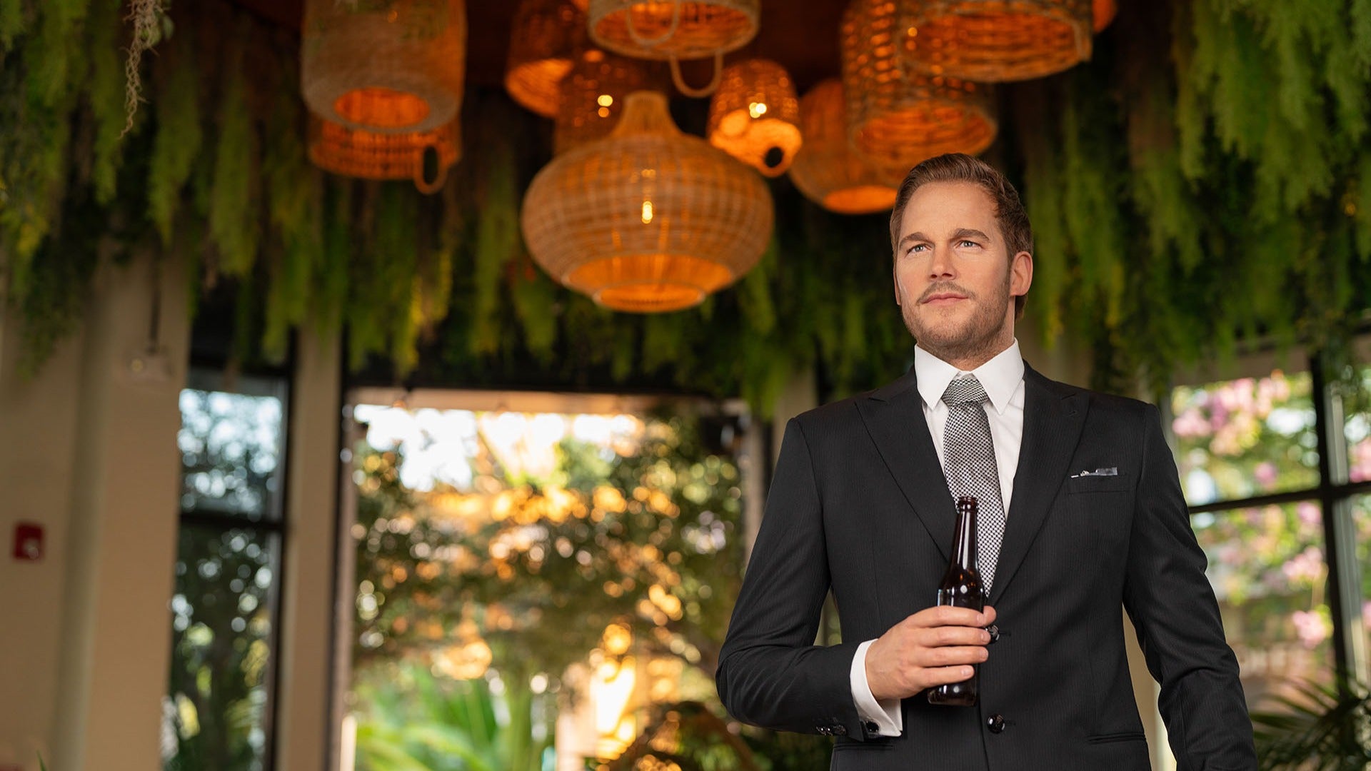wax figure of a man in a suit holding a bottle of beer