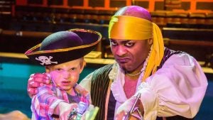 a man in pirate costume with a kid wearing a pirate hat and holding a sword