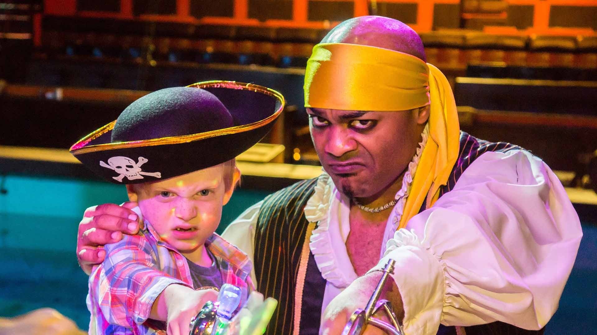 a man in pirate costume with a kid wearing a pirate hat and holding a sword