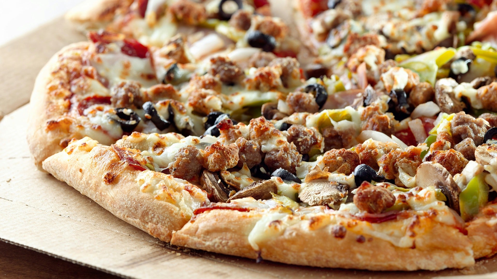 pizza topped with meat, olives, and other veggies