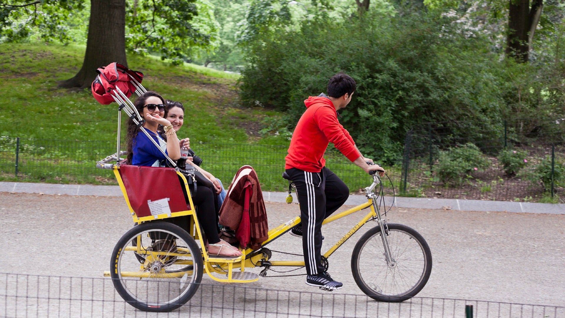 people riding a pedicab through the park with a driver