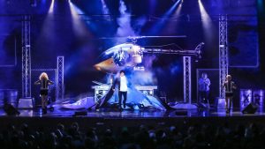 man performing on stage with visuals of a helicopter