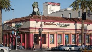 building exterior with posters, signages, and a dinosaur statue on top