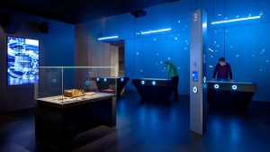 a blue room with exhibits and people interacting with them