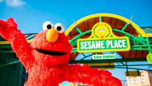 elmo posing in front of a sesame place sign