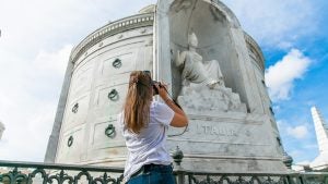 a girl taking a photo of a cemetery statue
