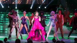 a group of performers in costumes dancing and singing on stage