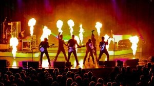 group of performers with instruments on stage with fire effects