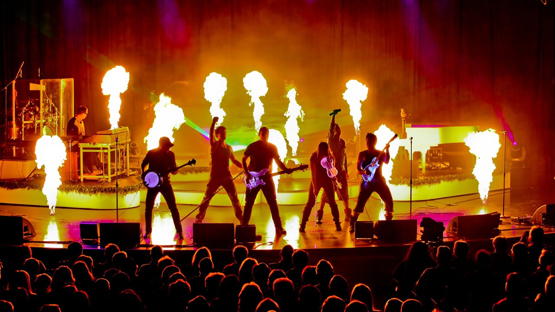 group of performers with instruments on stage with fire effects