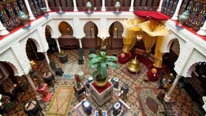 museum with lots of colorful fabrics, gold decorations, tiled floors, and plant in the middle