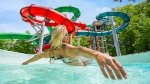 woman on a floatie with a view of water slides at the back