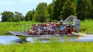 people aboard an airboat riding through a swamp