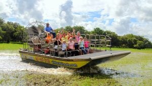 people aboard an airboat tour through a swamp