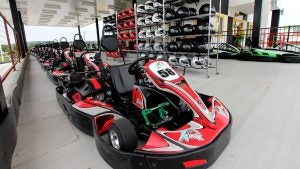 go karts in line at a track with a shelf of helmets on the side