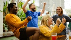 people in a sports bar cheering and drinking alcohol