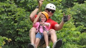 a zipline staff with a young girl waving