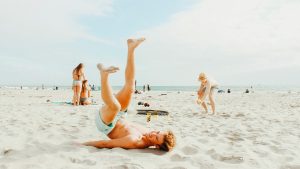 a boy playing on the beach with a family behind him and the ocean