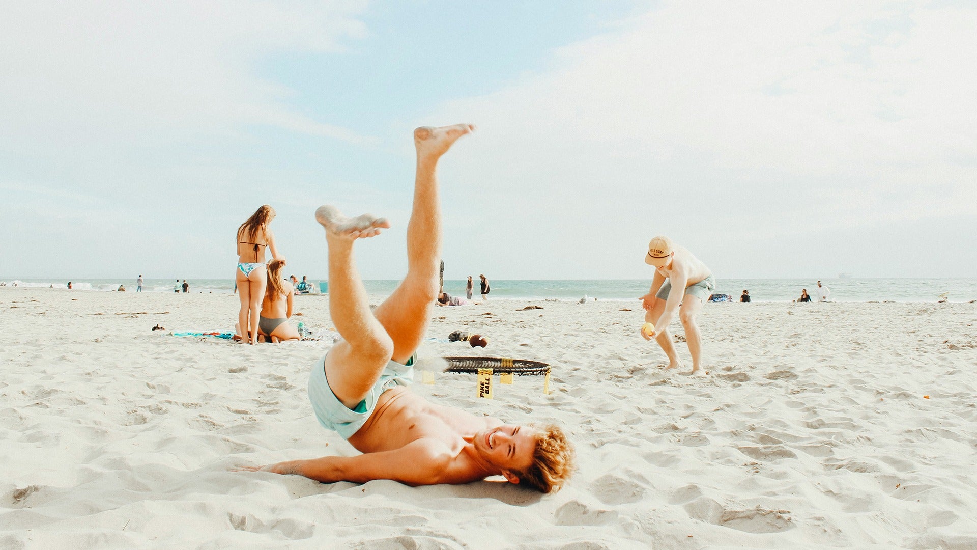 a boy playing on the beach with a family behind him and the ocean